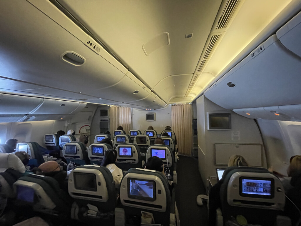 a group of people sitting in an airplane with monitors