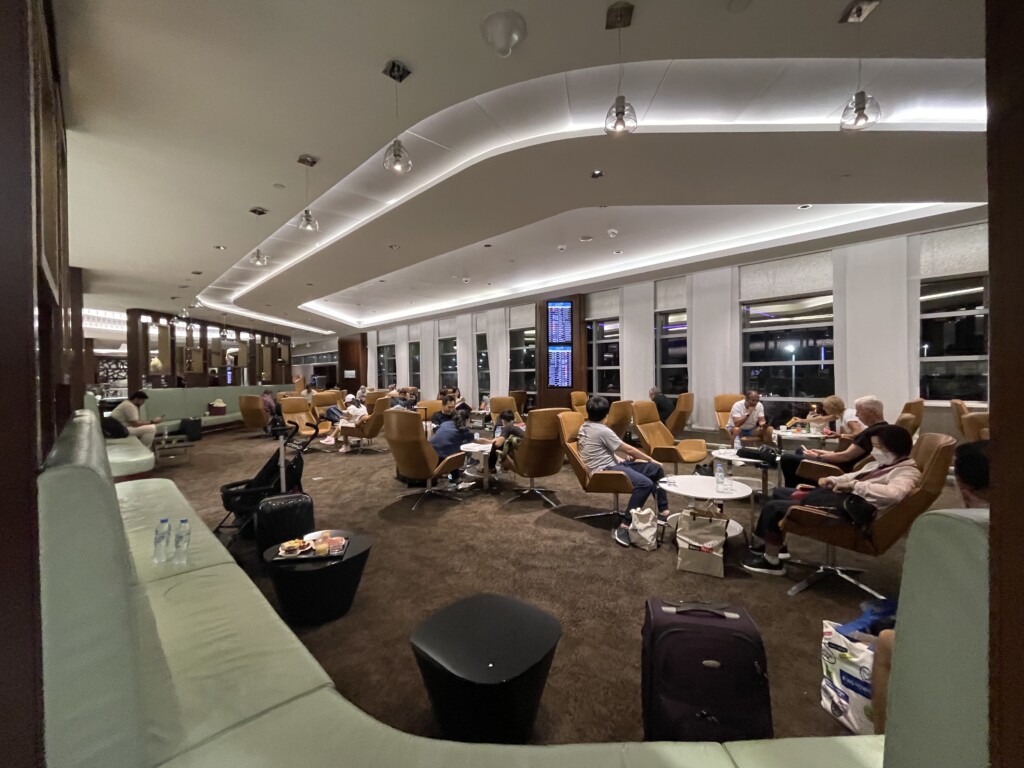 a group of people sitting in a room with chairs and luggage