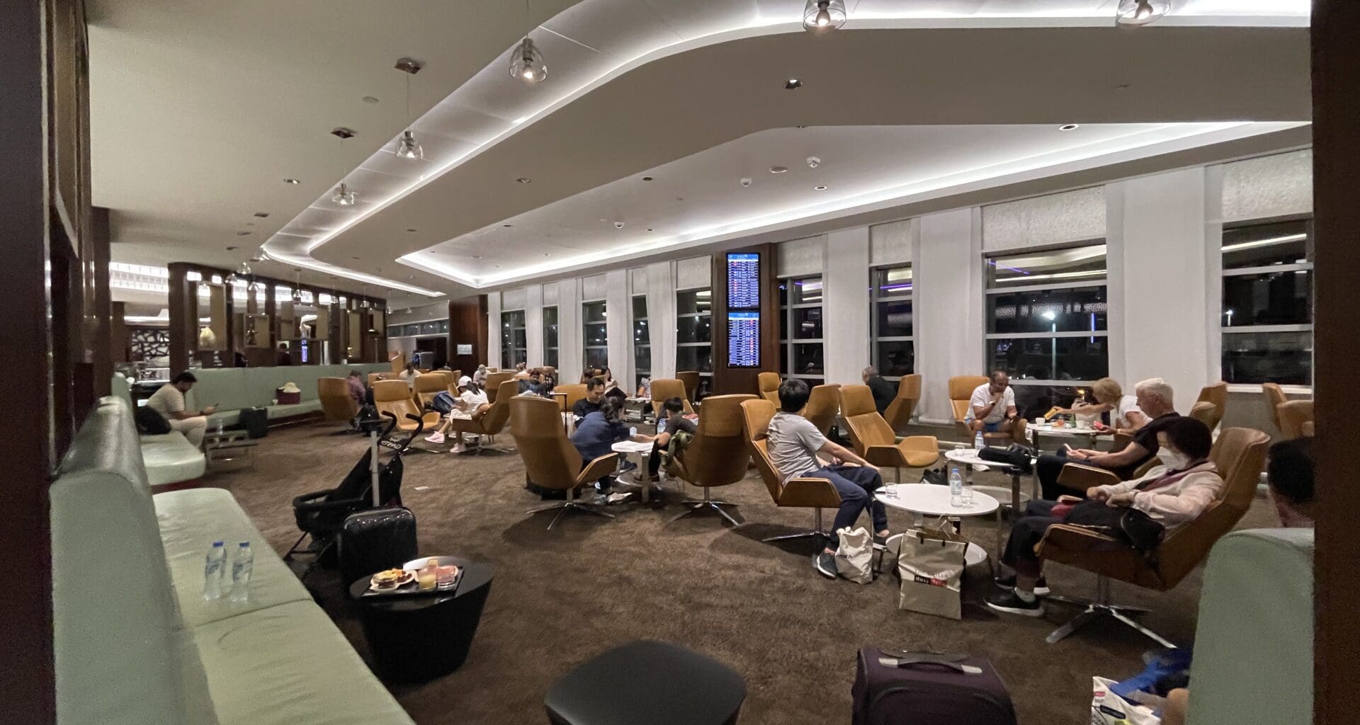 a group of people sitting in a room with chairs and luggage