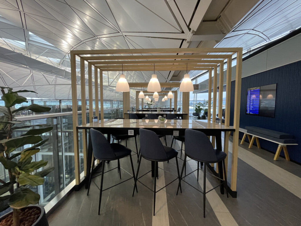 a table with chairs and a table in a room with a glass wall and a television