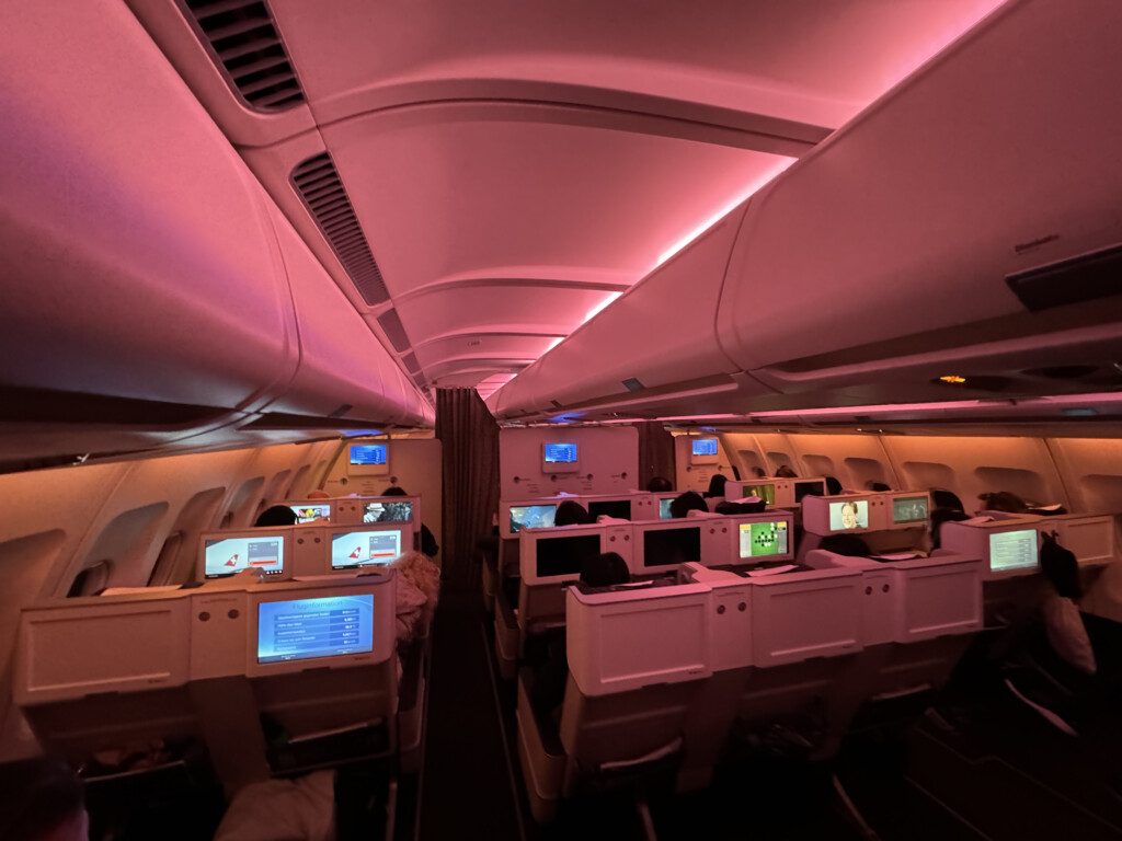 inside an airplane with rows of seats and monitors