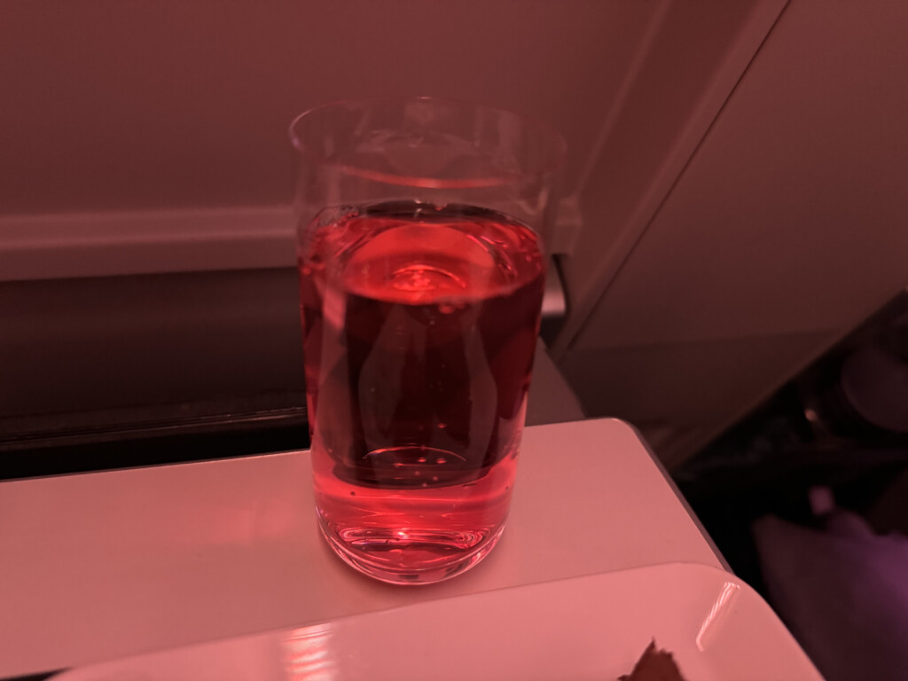 a glass of pink liquid on a white plate