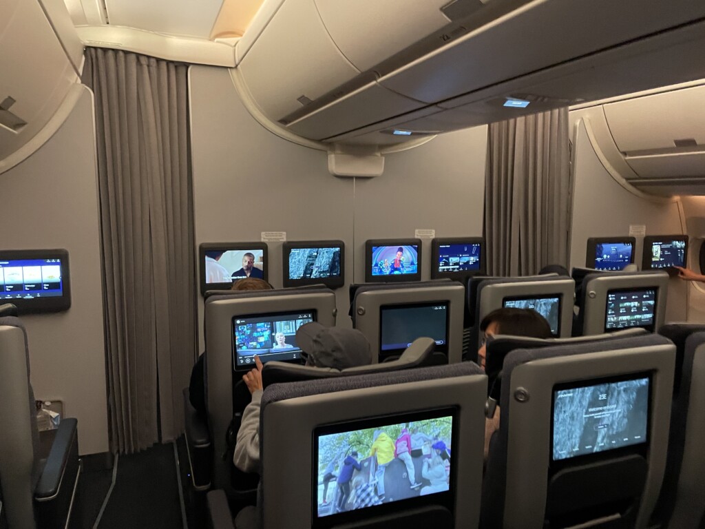 a group of people sitting in an airplane with monitors