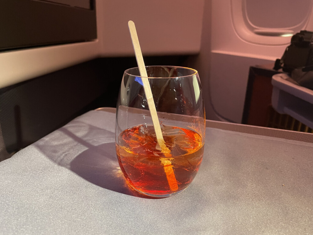 a glass with brown liquid and ice on a table