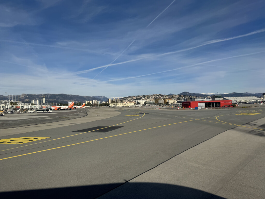 a runway with a red building and a city in the background