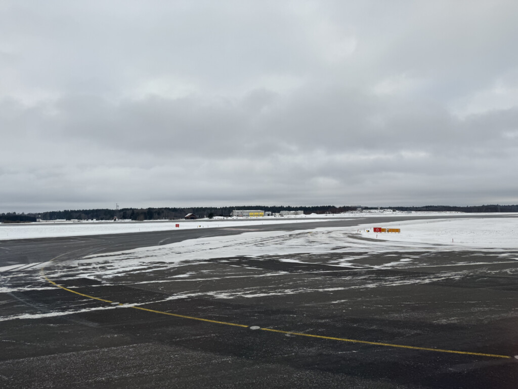 a snow covered ground with a yellow line and a building in the distance