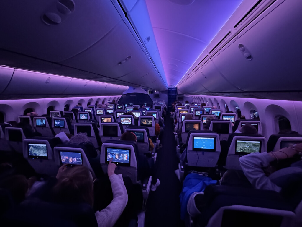 a group of people sitting in an airplane with monitors