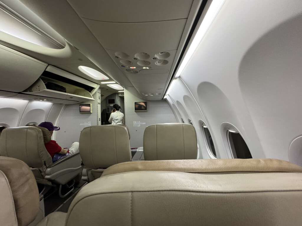 inside an airplane with seats and people in the back