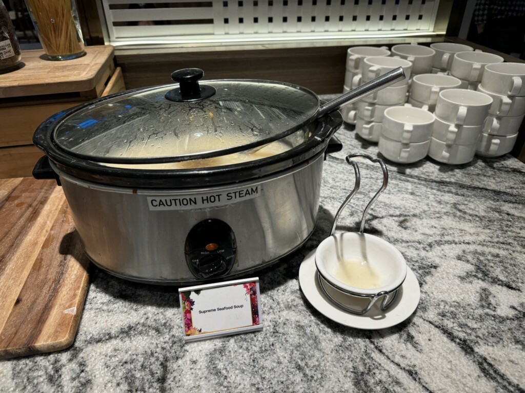 a crock pot with a lid and a bowl of soup on a counter