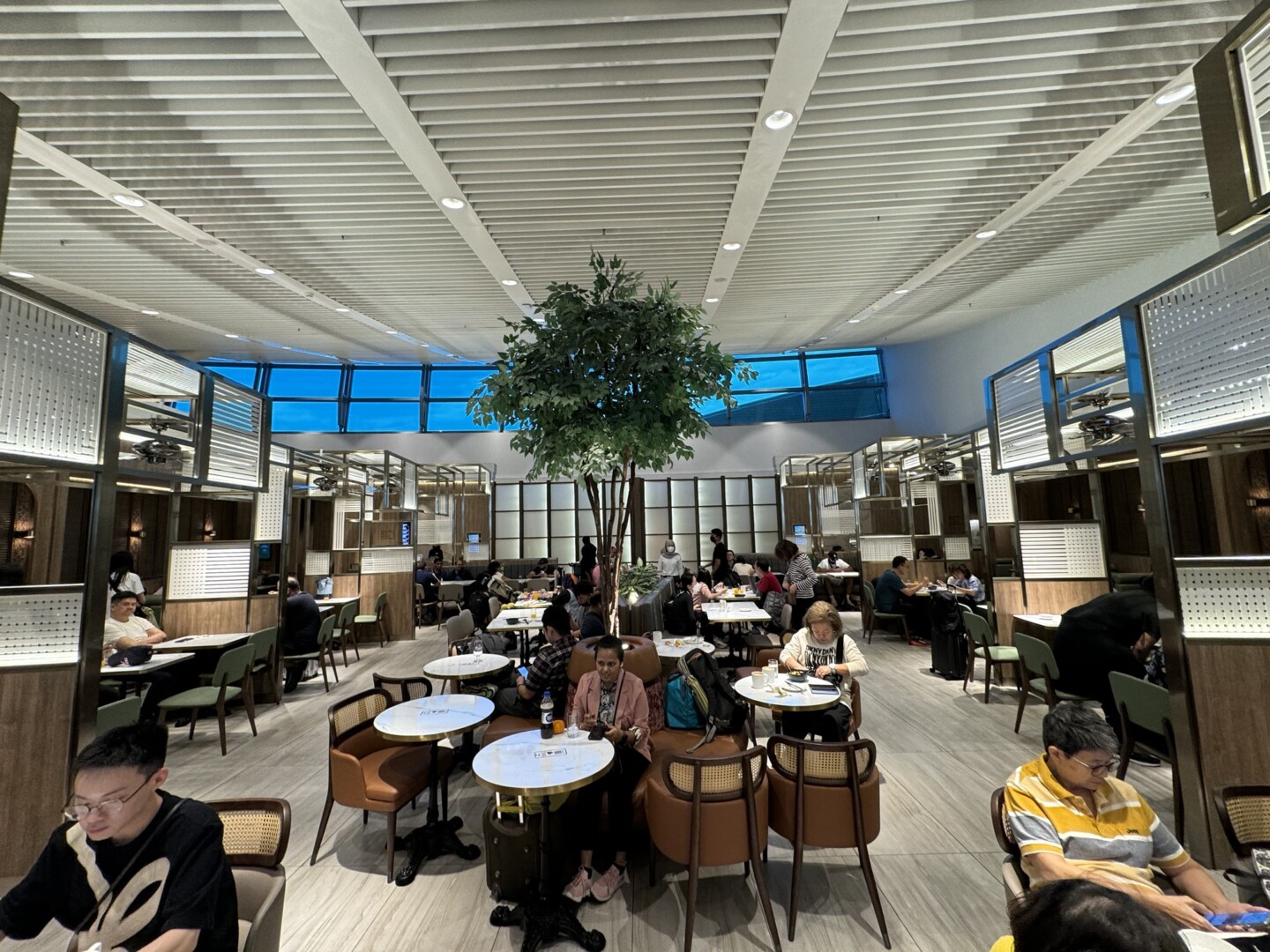 a group of people sitting at tables in a room with a tree