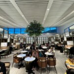 a group of people sitting at tables in a room with a tree