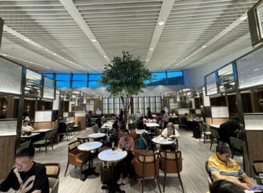 a group of people sitting at tables in a room with a tree