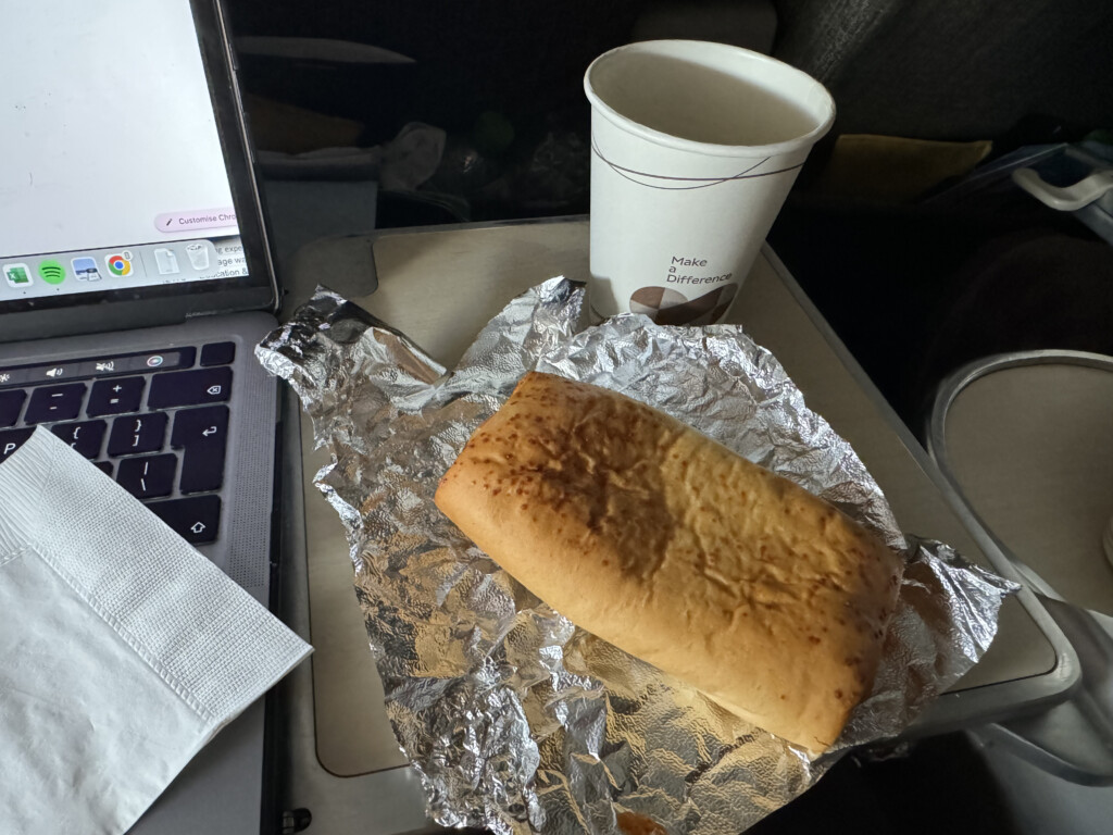 a loaf of bread on foil next to a cup of coffee