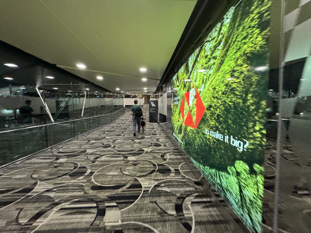 a man walking on a walkway with a large screen