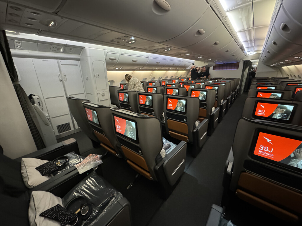 a group of people sitting in an airplane with monitors