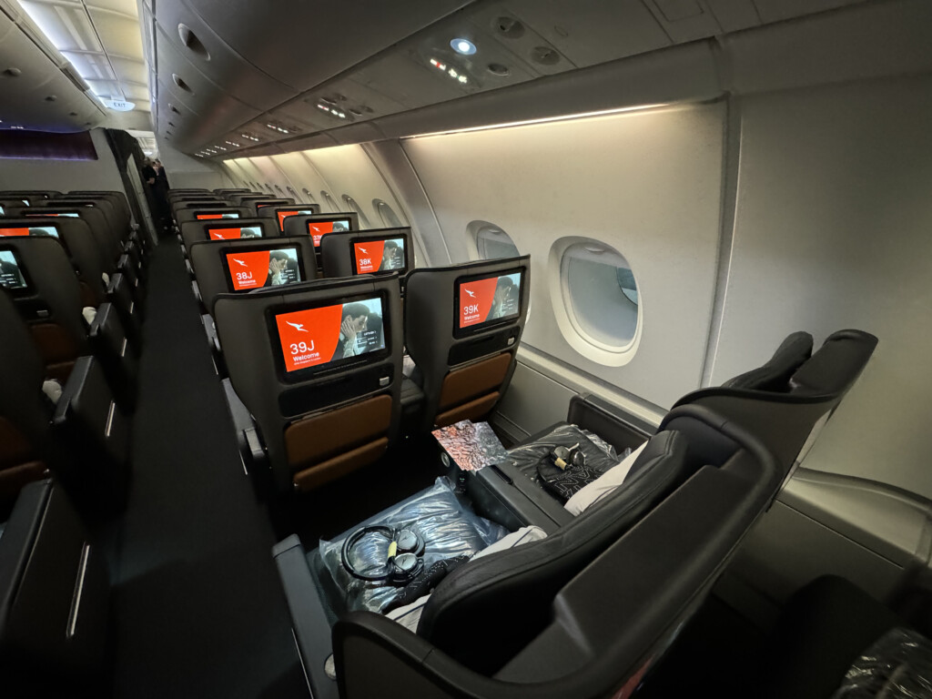 a row of seats with monitors on the side of the plane