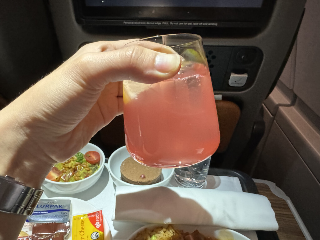 a hand holding a glass of pink liquid