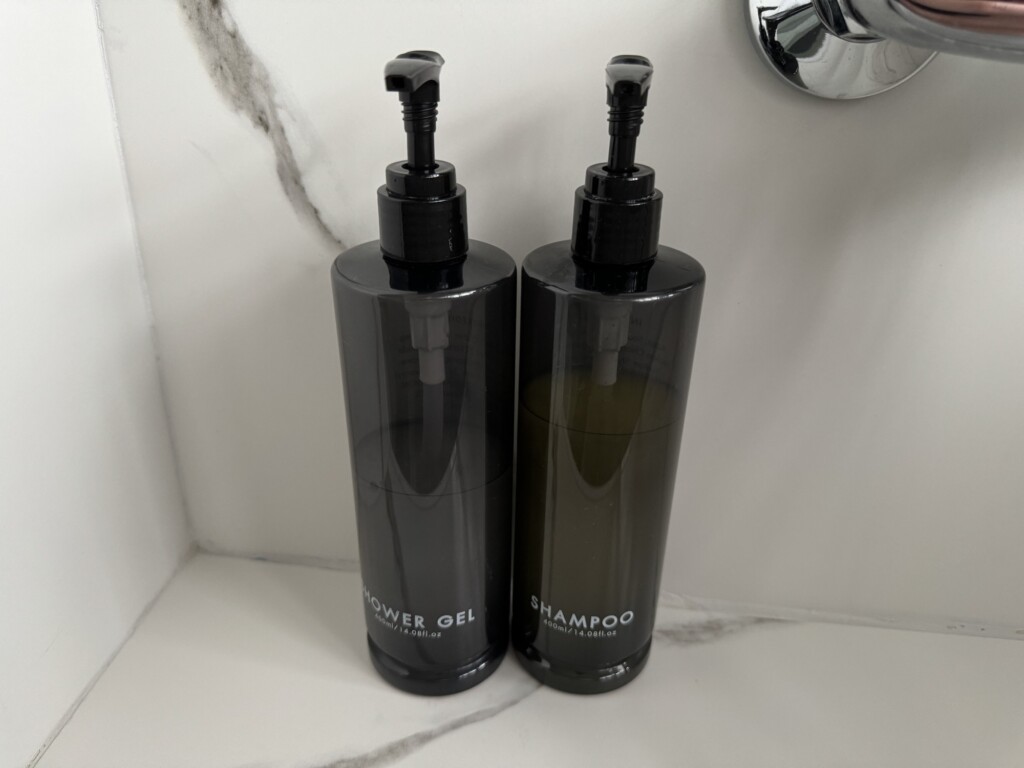 two black bottles with dispensers on a marble counter