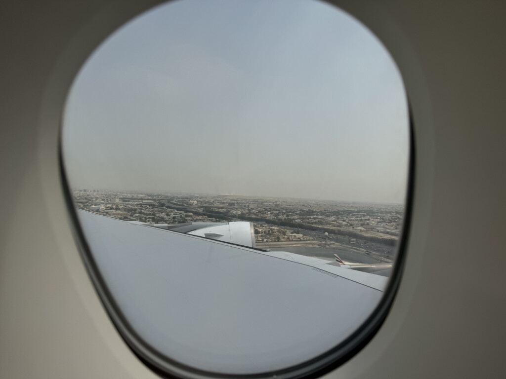 an airplane window with a city in the background