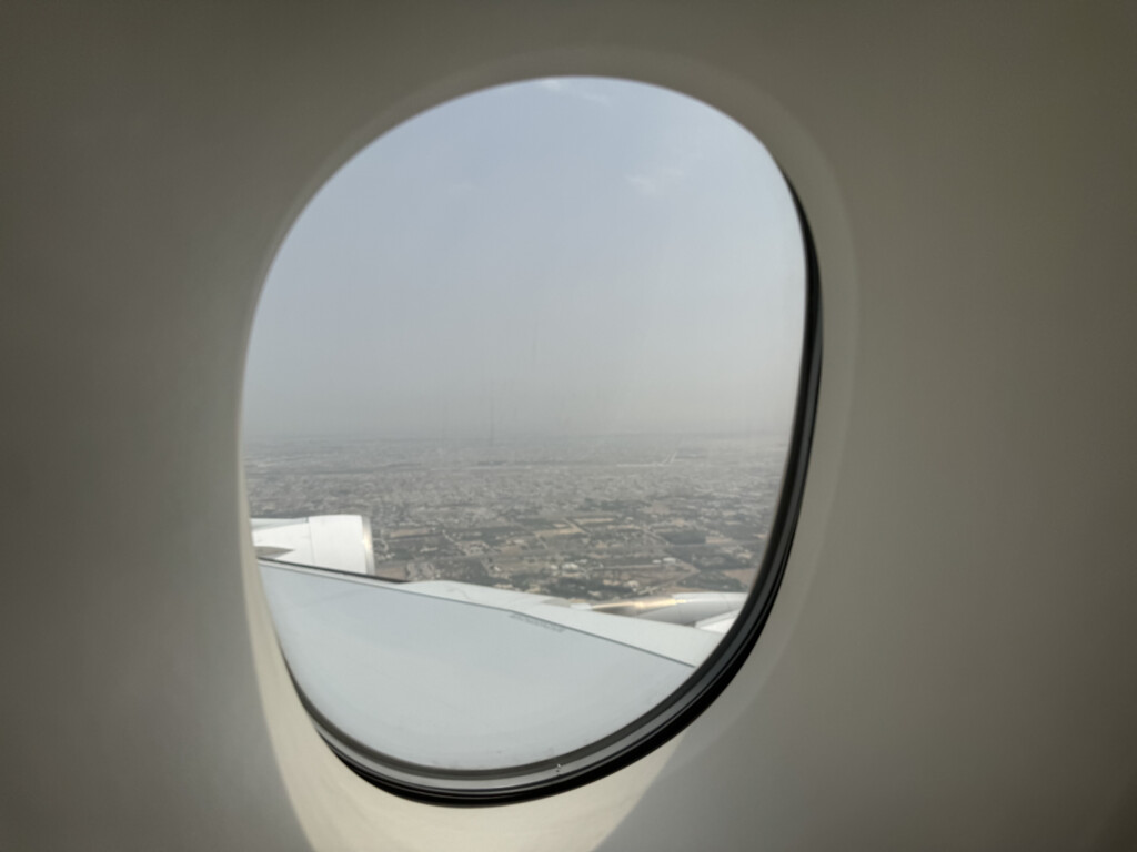 an airplane window with a city in the background