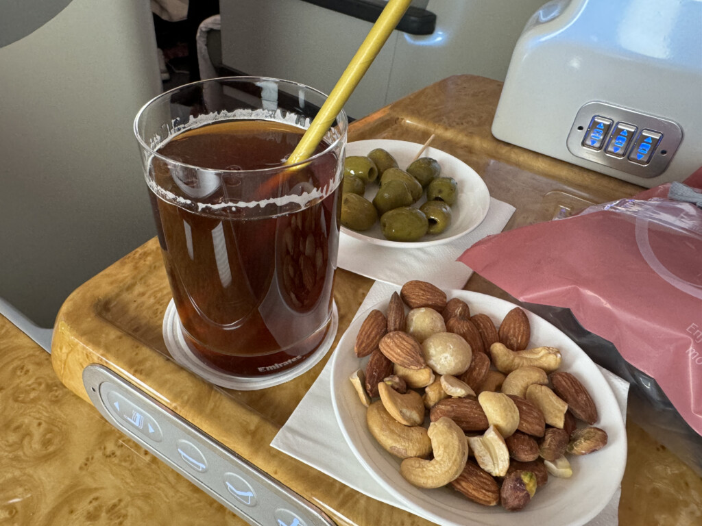 a bowl of nuts and a glass of liquid on a tray