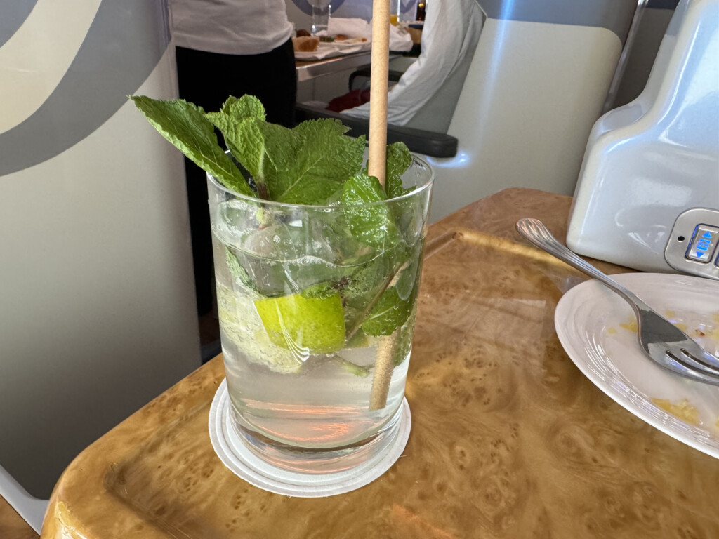 a glass with water and lime and mint leaves on a table