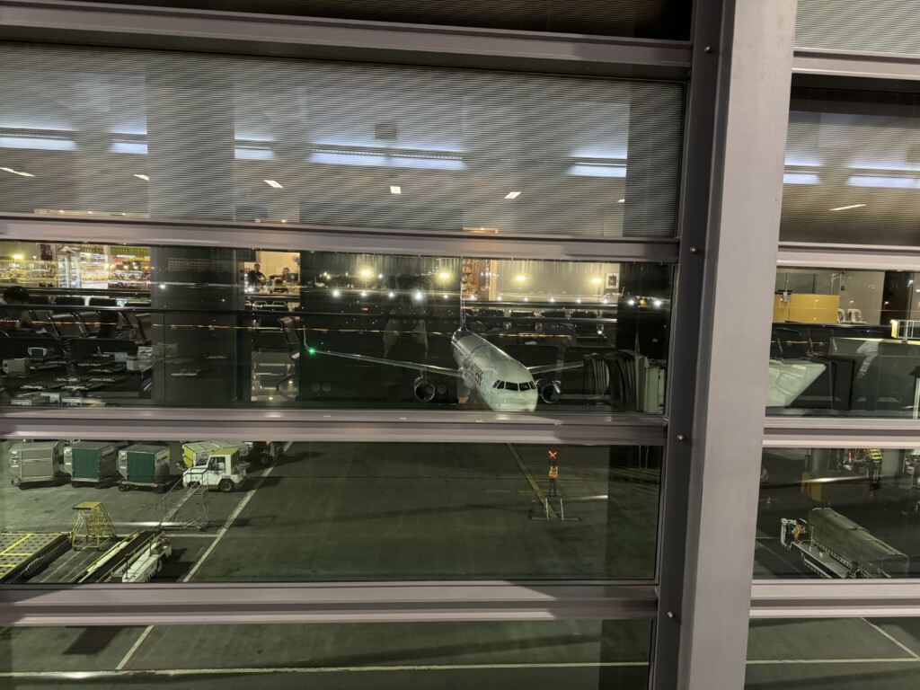 a window of an airport with a plane in the parking lot