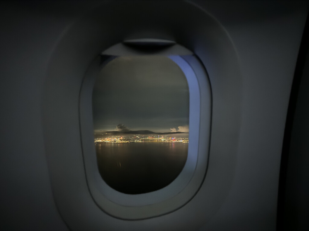 a window of an airplane with a city in the distance