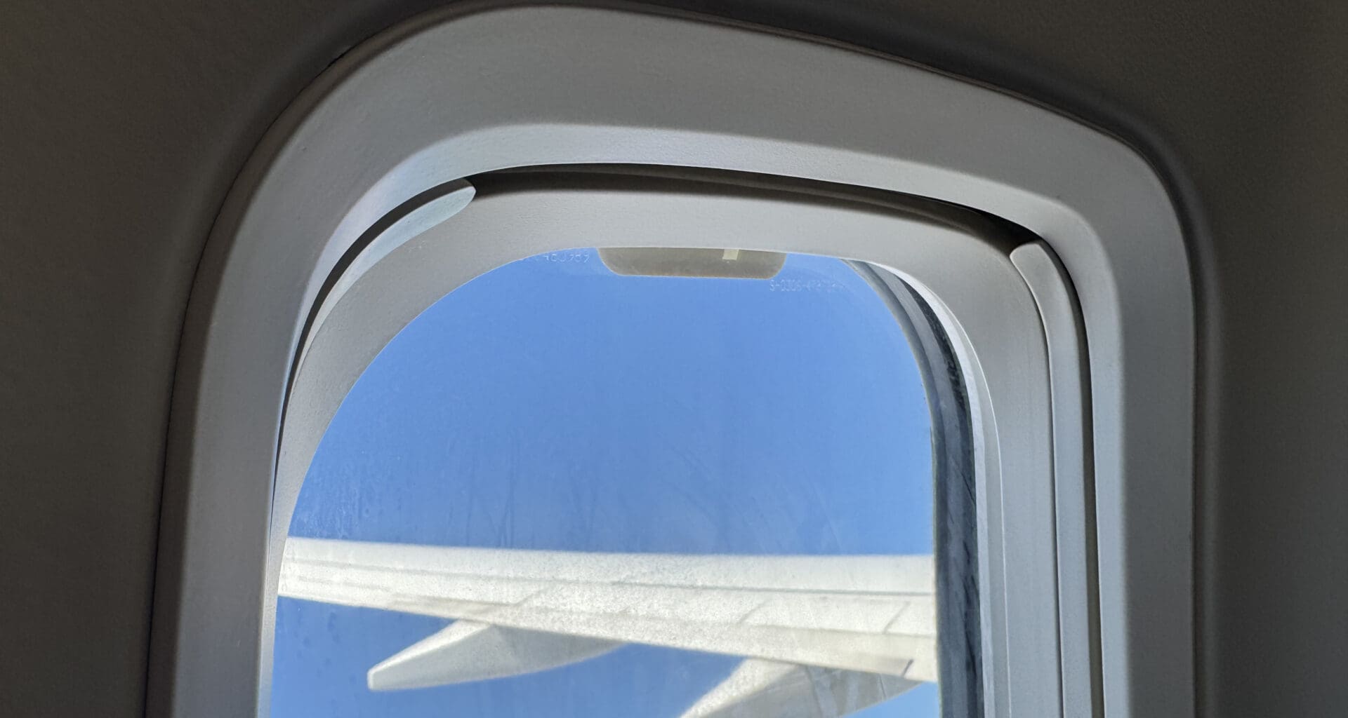 a window with a wing and blue sky