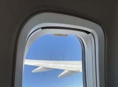 a window with a wing and blue sky