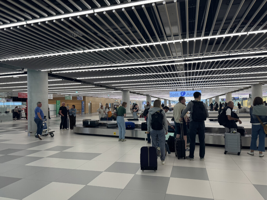 a group of people with luggage in an airport with MetLife Stadium in the background