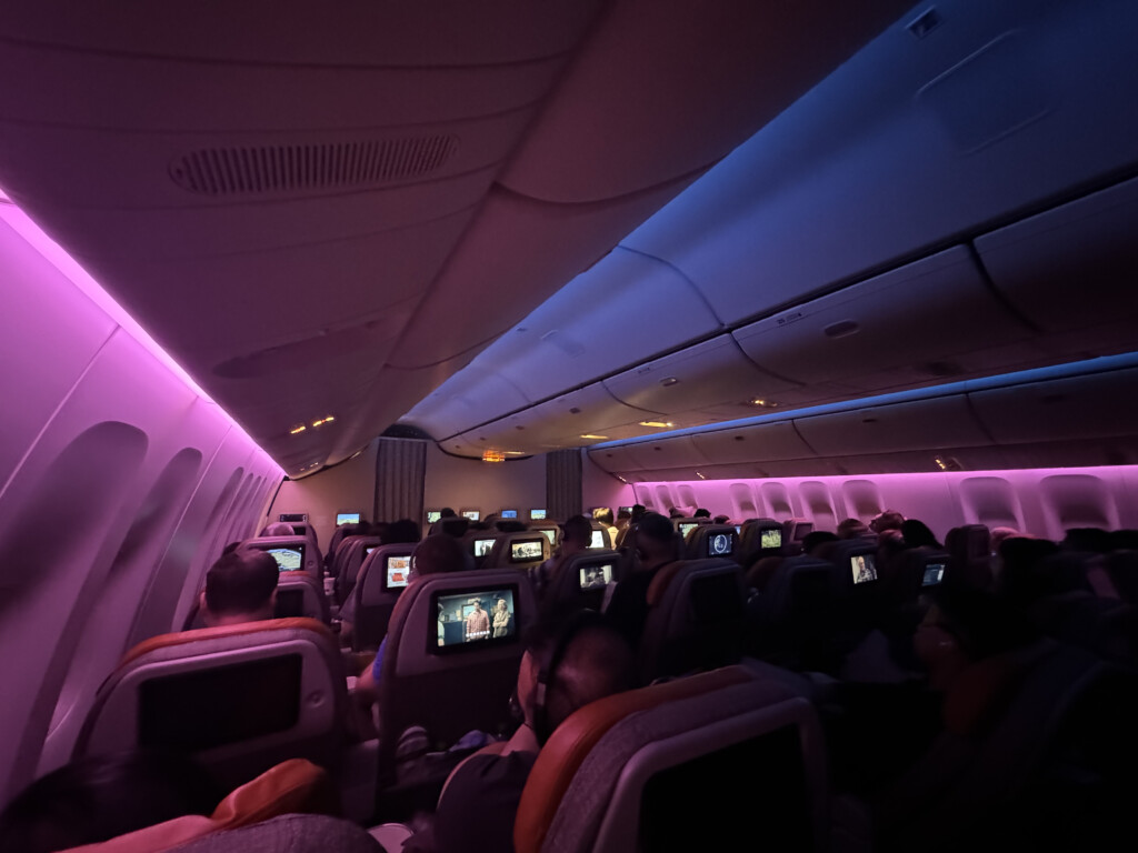 a group of people sitting in an airplane with a purple light