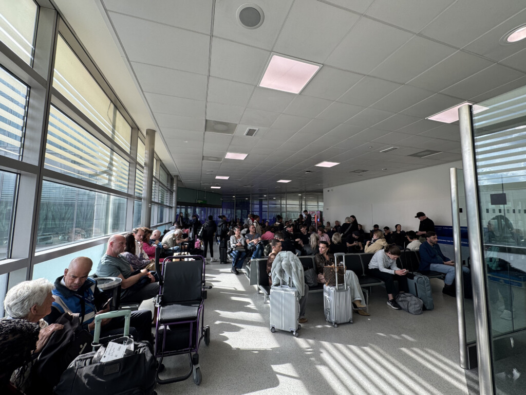 a group of people sitting in a room with luggage