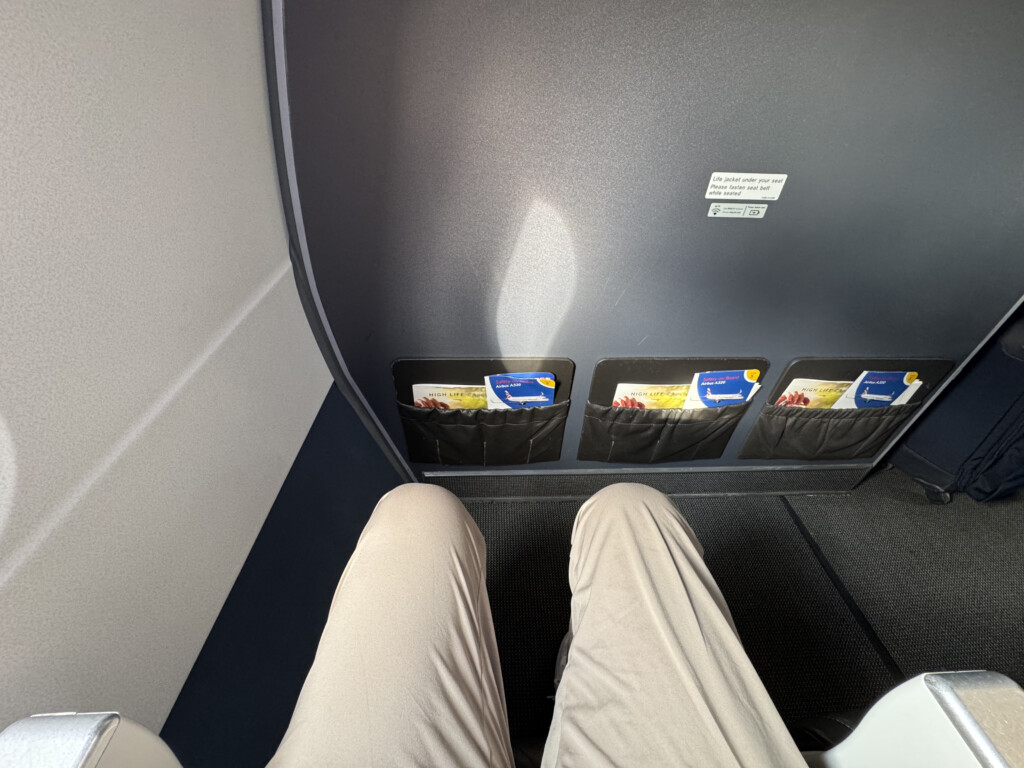 a person's legs in a seat with a pocket in the back