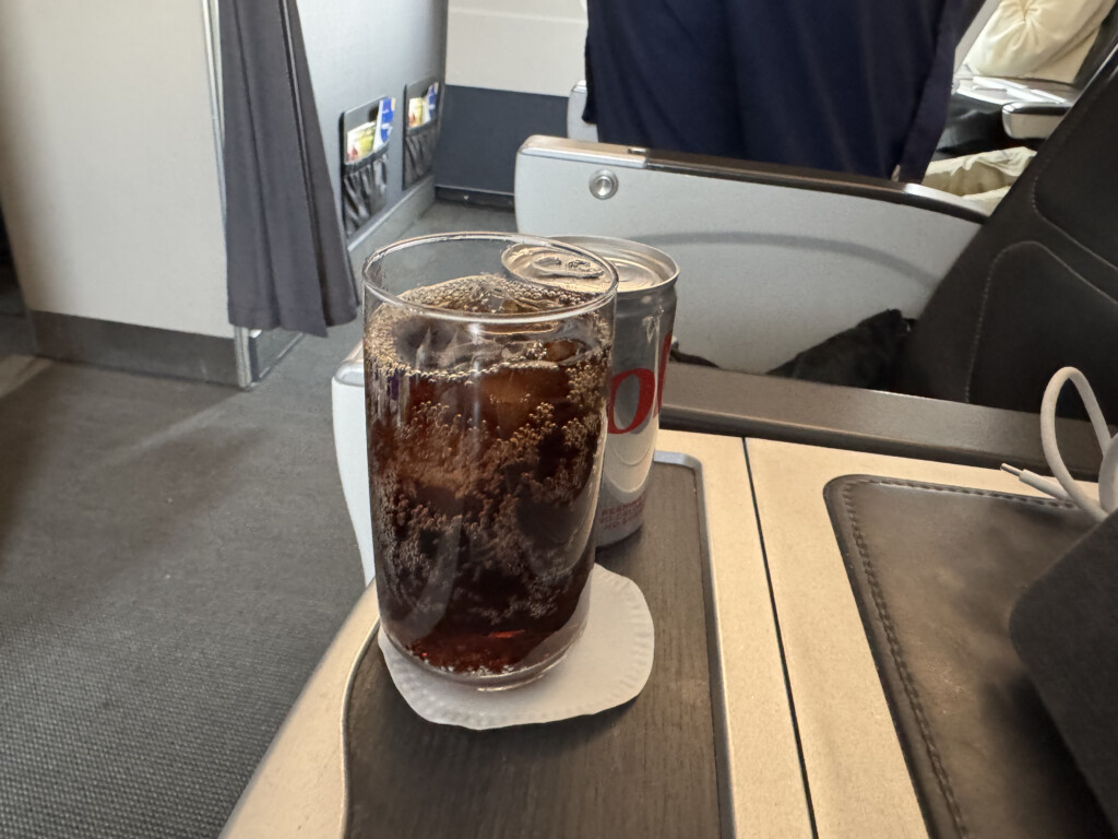 a glass of soda and can on a tray