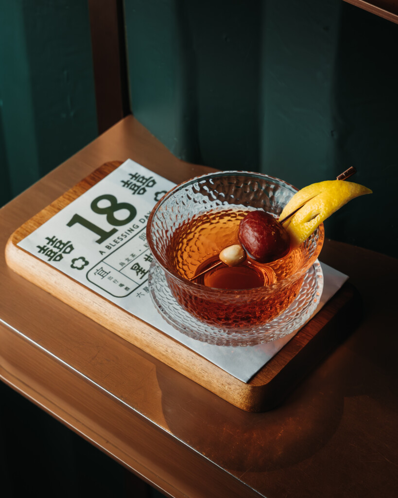 a glass of liquid with fruit on a wooden surface