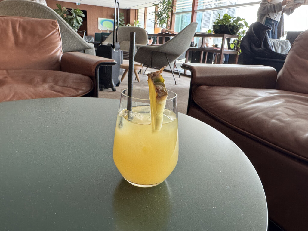 a glass of yellow liquid with a pineapple on a table