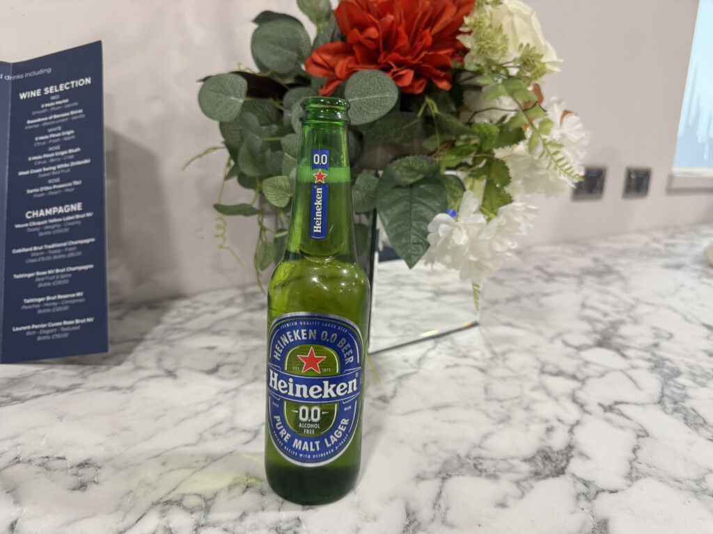 a green bottle of beer next to a bouquet of flowers