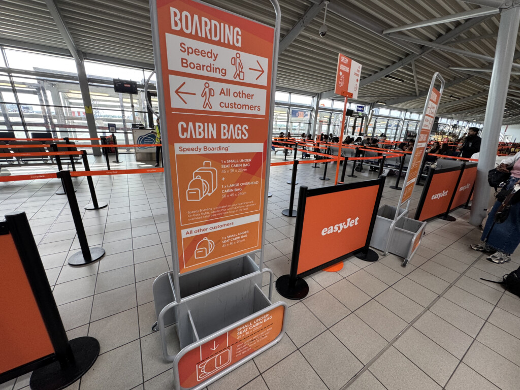 signs in a terminal with a line of luggage
