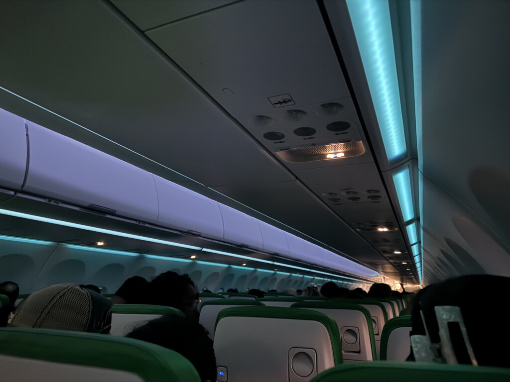 inside an airplane with green seats and lights