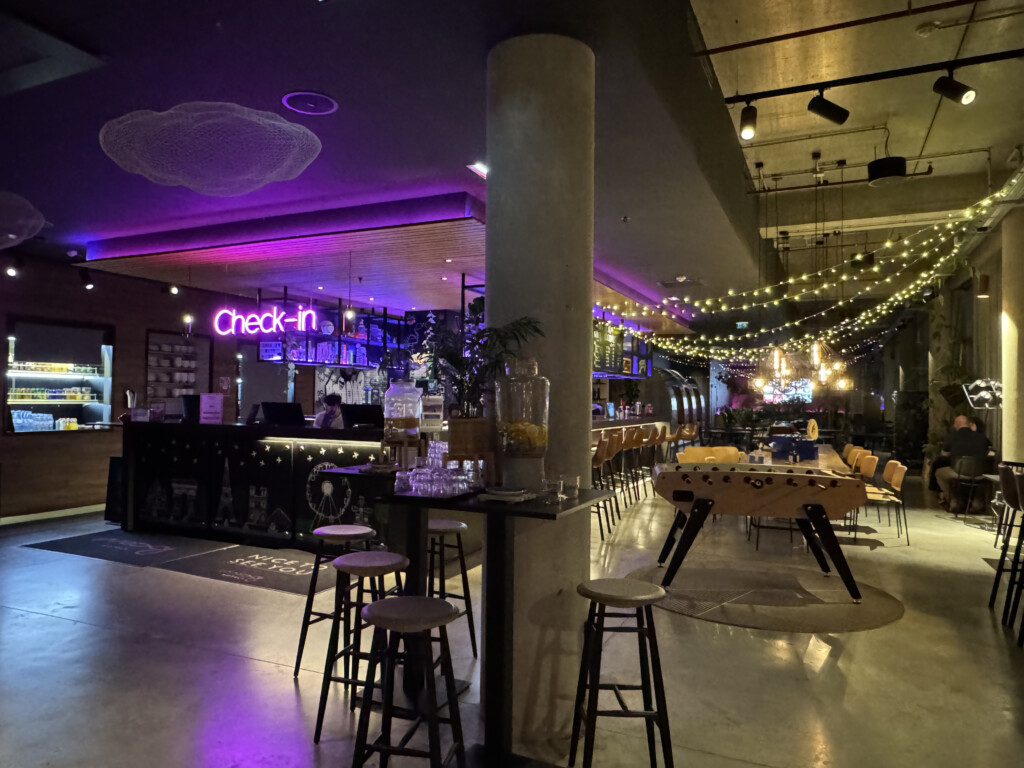 a bar with tables and chairs in a room with purple lights