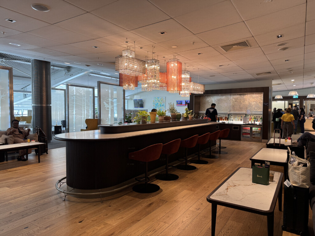 a bar with chairs and a table with a man standing behind it