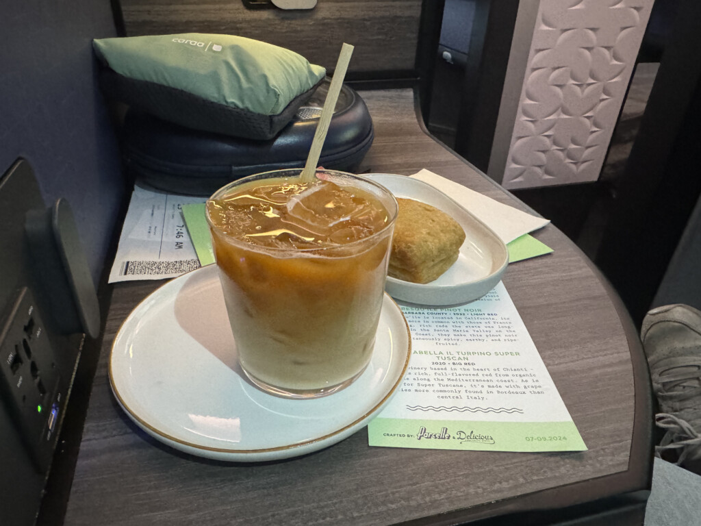 a glass of liquid with a straw on a plate with food on a table