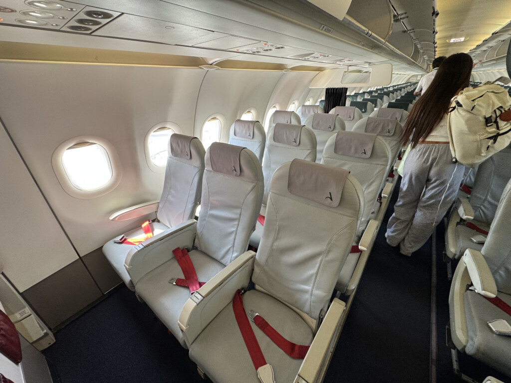 a person standing in a row of white seats on an airplane