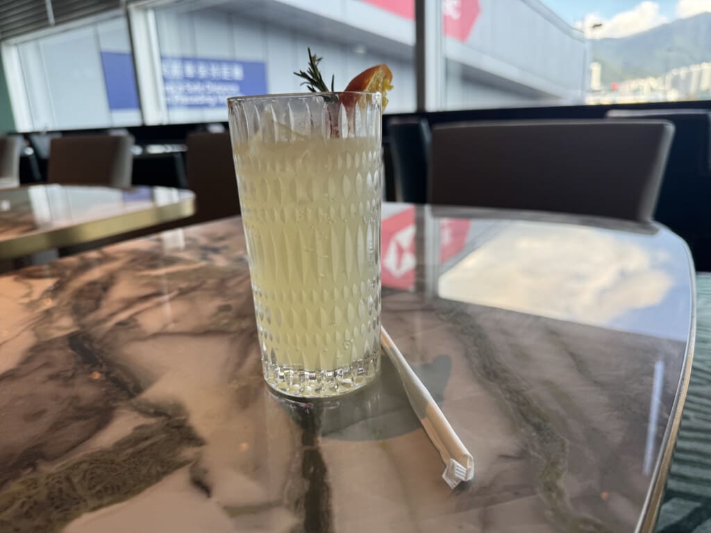 a glass of drink with a straw and a piece of rosemary on a marble table