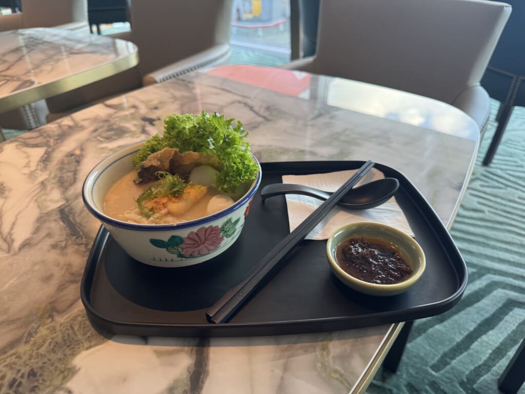 a bowl of soup with vegetables and sauce on a tray