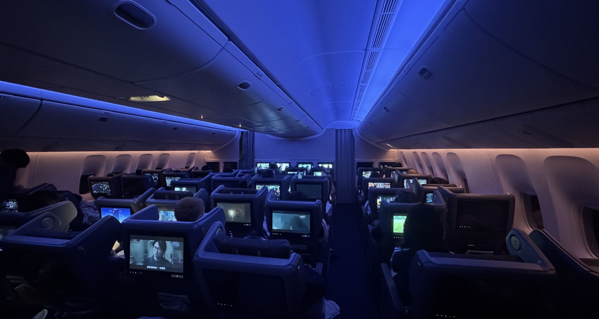 a group of people sitting in an airplane with monitors