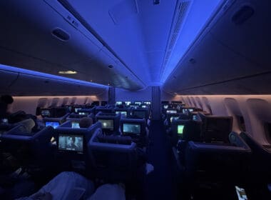 a group of people sitting in an airplane with monitors