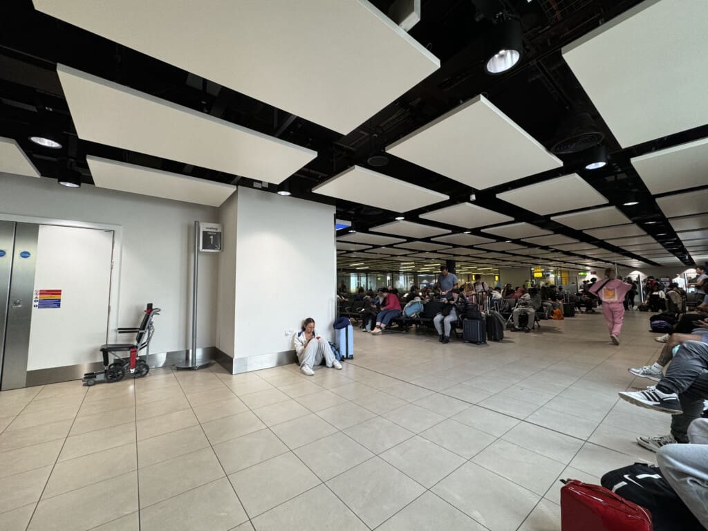 a group of people sitting in a large room with luggage