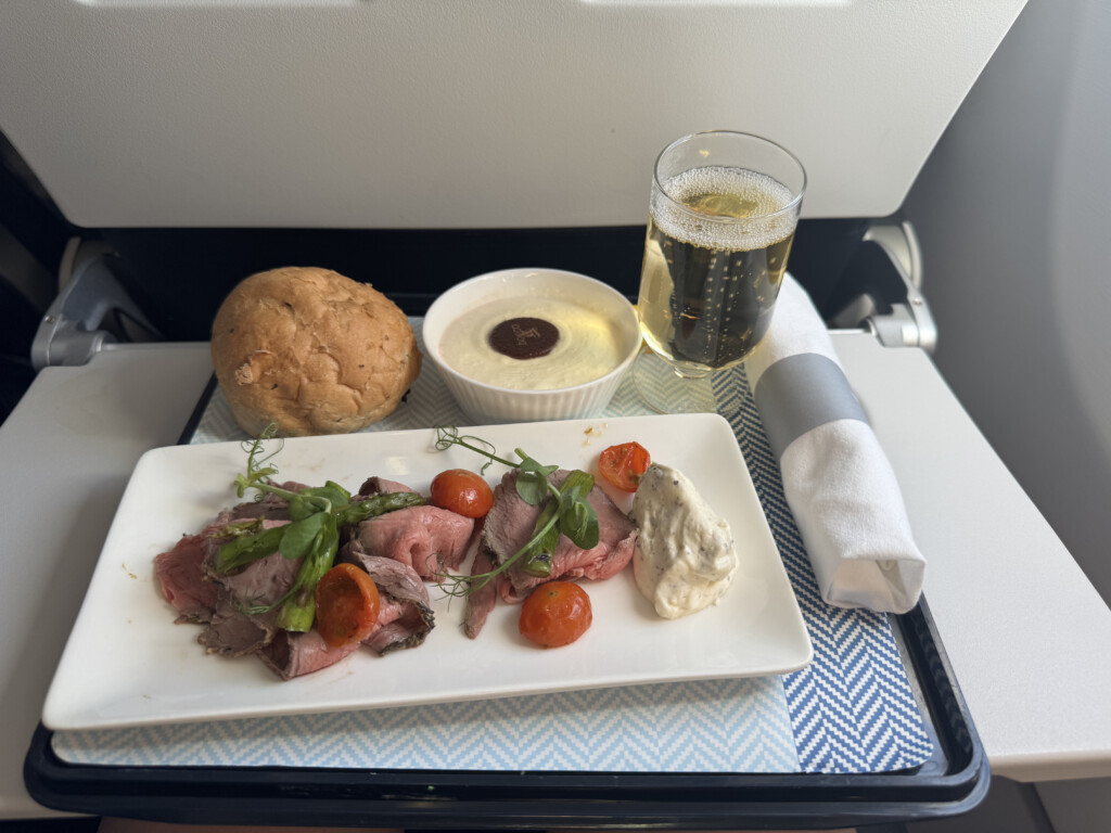 a plate of food and a glass of beer on a tray